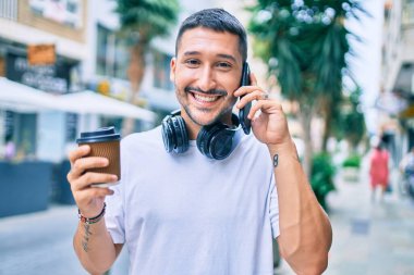 Genç İspanyol adam akıllı telefondan konuşuyor. Şehir caddesinde kahve içiyor..