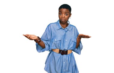 Sıradan kıyafetler giyen, kafası karışmış, elleri ve kolları havada genç bir Afrikalı Amerikalı kadın. şüphe kavramı. 