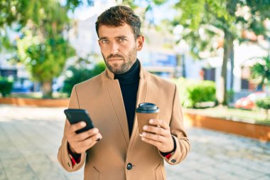 Zarif ceketli yakışıklı bir iş adamı. Açık havada akıllı telefon kullanıyor.