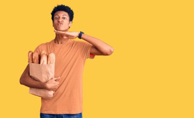 Genç Afro-Amerikalı bir adam, elinde ekmek torbası, elinde bıçakla boğazını kesiyor, saldırganlığı şiddetli bir şiddetle tehdit ediyor. 