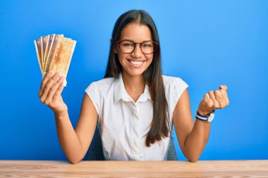 500 Norveç kronu tutan güzel İspanyol kadın gururla haykırıyor, zaferi ve başarıyı kutluyor. 