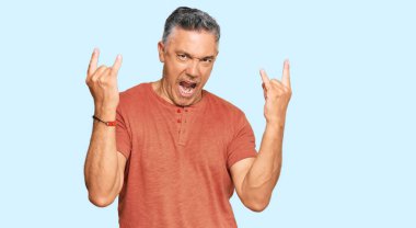 Yakışıklı, orta yaşlı, günlük kıyafetler giymiş çılgın bir ifadeyle bağıran elleri havada rock sembolü yapan bir adam. Müzik yıldızı. ağır kavram. 