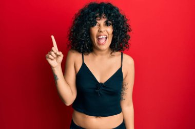 Kolsuz gömlekli, gündelik tarzda giyinen genç İspanyol kadın başarılı bir fikri işaret ediyor. Heyecanlı ve mutlu. Bir numara.. 