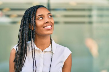 Genç Afrikalı Amerikalı kadın gülümseyerek şehirde mutlu mesut duruyor..