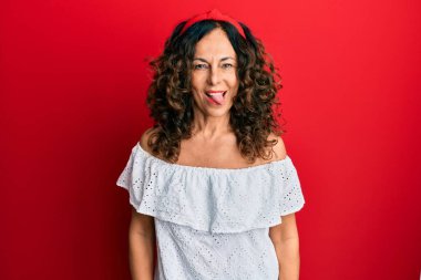 Orta yaşlı İspanyol kadın, sıradan kıyafetler giyiyor. Dilini komik bir ifadeyle dışarı çıkarıyor. duygu kavramı. 