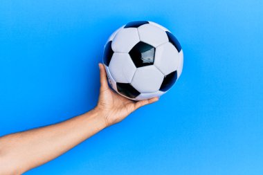 Futbol topunu mavi arka planda tutan İspanyol bir adamın eli..