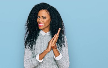 Orta yaşlı Afro-Amerikalı kadın günlük giysiler giyip alkışlıyor ve mutlu, neşeli ve gururlu elleri bir arada alkışlıyor. 