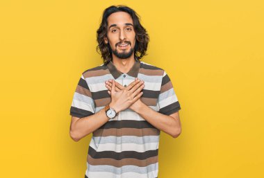 Gündelik kıyafetler giyen genç İspanyol adam elleri göğsünde, gözleri kapalı ve yüzünde minnet dolu bir jest ile gülümsüyor. sağlık kavramı. 