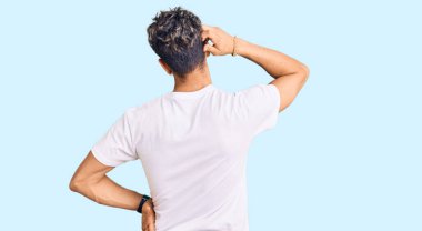 Gündelik beyaz tişört giyen genç yakışıklı adam, elleri kafasında şüpheyi düşünüyor. 