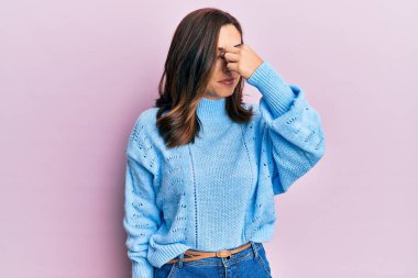 Genç esmer kadın pembe arka plan üzerine sıradan bir kazak giyer. Burnu ve gözleri ovuşturur, yorgunluk ve baş ağrısı hisseder. Stres ve hüsran kavramı. 