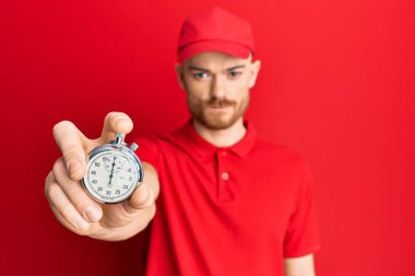 Young redhead man wearing delivery uniform and countdown clock thinking attitude and sober expression looking self confident  clipart