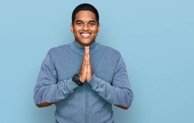 Genç, yakışıklı, sıradan bir eşofman üstü giyen, elleri birarada dua eden, kendine güvenen, gülümseyen İspanyol bir adam.. 