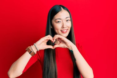 Gündelik kıyafetler giyen, aşık gülümseyen, elleriyle kalp sembolü yapan genç Çinli bir kadın. romantik kavram. 