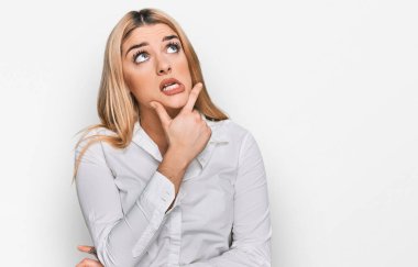 Gündelik giysiler giyen genç beyaz kadın bir soru hakkında endişeli ve gergin bir şekilde düşünüyor. 