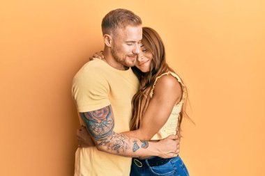 Genç bir çift kız arkadaş ve erkek arkadaş kucaklaşıyorlar ve birbirlerine sarılıyorlar mutlu ve pozitif, kendinden emin gülümsüyorlar. Sevgi ve özgüven. 