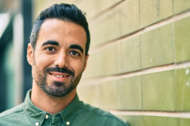 Genç İspanyol adam gülümseyerek şehirde mutlu mesut dikiliyor..