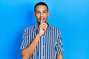 Gündelik giysiler giymiş genç Afro-Amerikan bir adam sessiz olmak istiyor. sessizlik ve gizli konsept. 