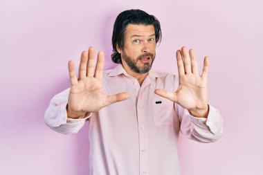 Orta yaşlı, günlük kıyafetler giyen, korku ifadesinden korkan ve dehşete düşmüş beyaz bir adam. El kol hareketi yapmayı kes, şok içinde bağır. panik konsepti. 