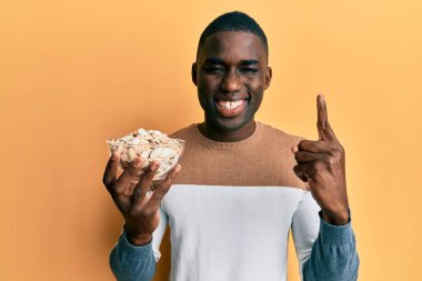 Genç Afrikalı Amerikalı bir adam elinde kabak tohumlarıyla gülümsüyor bir fikirle ya da soruyla gülümsüyor mutlu bir yüzle, bir numara 