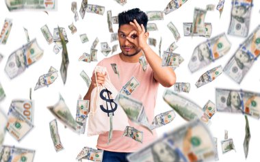 Yakışıklı Latin Amerikalı genç adam dolar sembollü para çantası tutuyor. Gülümsüyor. Tamam.