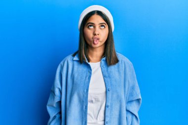 Tatlı yün şapkalı genç Latin bir kadın dudaklarıyla balık suratı yapıyor, çılgınca ve komik bir jest. Komik ifade. 