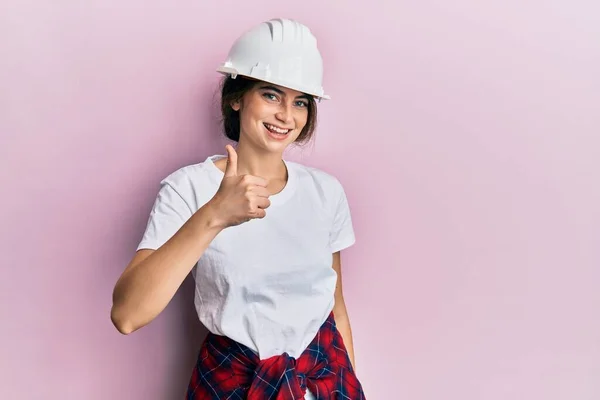年轻的高加索女人戴着硬礼帽 用手拿着快乐的大拇指做手势 赞成的表情看着相机显示的成功 — 图库照片