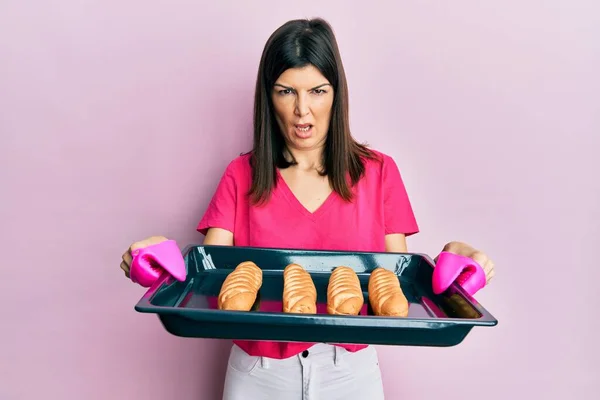 Young Hispanic Woman Holding Homemade Bread Shock Face Looking Skeptical — Stock Photo, Image