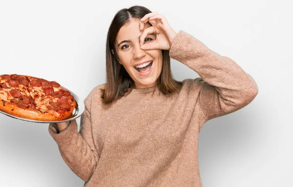 Fiatal Gyönyörű Kezében Olasz Pizza Mosolyogva Boldog Csinál Rendben Jel — Stock Fotó