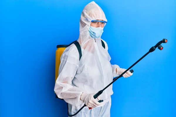 科维德专业人员 身穿防污防护服和消毒剂喷雾 在蓝色背景上对表面进行除污和消毒 — 图库照片