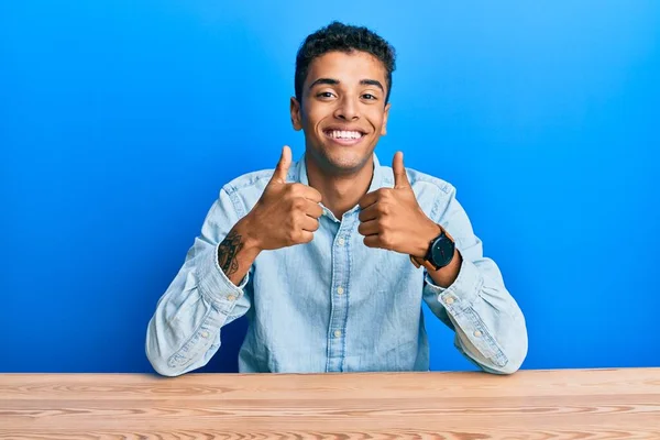 잘생긴 아프리카 미국인 남자가 테이블 손으로 긍정적 몸짓을 손가락으로 웃으며 — 스톡 사진