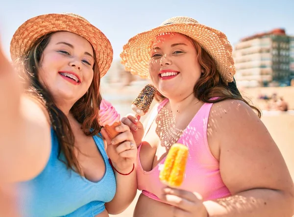 二つプラスサイズ太りすぎ姉妹双子女性食べる甘いですアイスクリームにザビーチで夏休み — ストック写真
