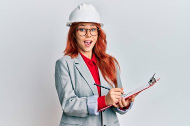 Genç kızıl saçlı kadın mimar kasketi takıyor. Çılgınlığı kutluyor ve başarıya hayret ediyor. Gözleri açık, heyecanlı çığlıklar atıyor.. 