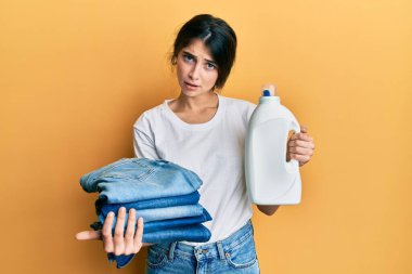 Çamaşır yıkayan, çamaşır yıkayan, çamaşır deterjanı şişesi tutan, şok olmuş, kuşkucu ve alaycı görünen, ağzı açık bir şekilde şaşırmış genç beyaz kadın. 