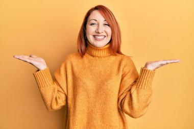 Güzel kızıl saçlı kadın, mutlu ve serin bir gülümsemeyle avucu açık bir şekilde sunum yapıyor. diş gösterme. 