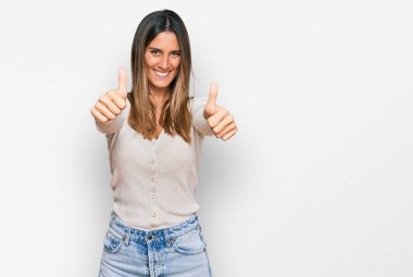 Gündelik giysiler giyen genç bir kadın elleriyle olumlu bir jest yapıyor. Gülümsüyor ve başarı için seviniyor. kazanan jest. 