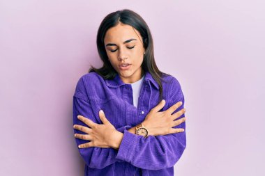 Genç esmer kadın, günlük kıyafetler giyiyor. Kış soğuğu için titriyor ve donuyor. Yüzünde üzgün ve şok ifadesi var. 