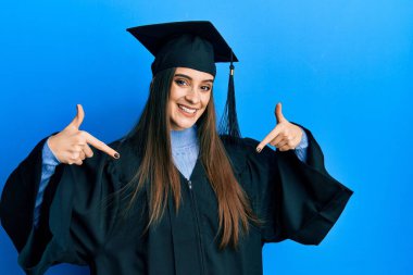 Mezuniyet şapkası ve tören cübbesi giyen güzel esmer bir kadın. Kendine güvenen, yüzünde gülümseme olan, kendini gururlu ve mutlu gösteren bir kadın.. 