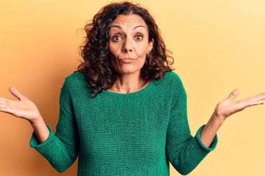 Orta yaşlı, güzel bir kadın sıradan bir süveter giyiyor ve kolları açık, hiçbir fikri yok ve şüpheli bir yüzü var.. 