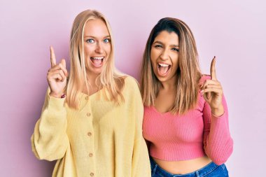 Pembe arka planda yan yana duran iki arkadaş başarılı bir fikri işaret ediyor. Heyecanlı ve mutlu. Bir numara.. 