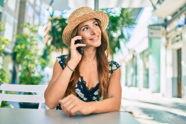 Genç İspanyol kadın tatilde. Şehir caddesinde akıllı telefondan konuşuyor..