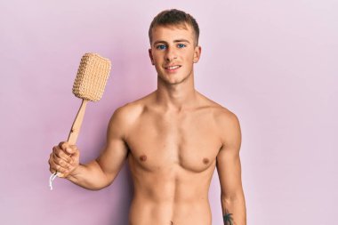 Beyaz, üstsüz, duş süngeri tutan genç bir adam. Olumlu ve mutlu görünüyor. Kendine güvenen bir gülümsemeyle dişlerini gösteriyor. 