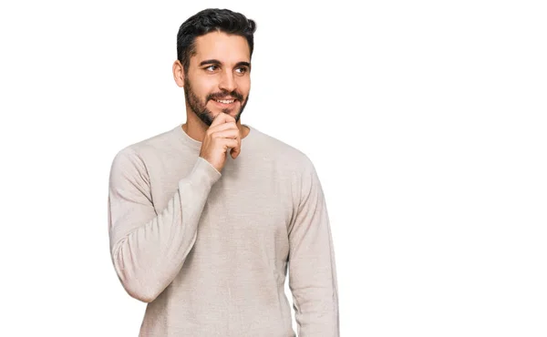 若いヒスパニック系の男性の質問については 集中的な表現を考えて顎に手でカジュアルな服を着て 思慮深い顔で笑顔 疑わしい概念 — ストック写真