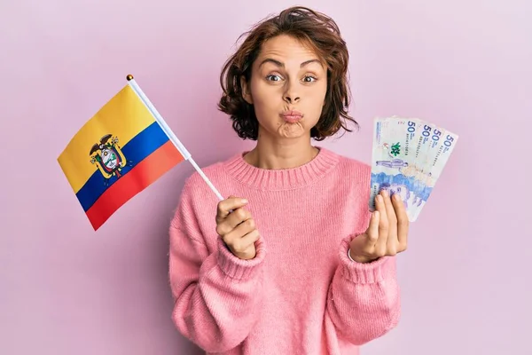 コロンビアの旗を持っている若いブルネットの女性と面白い顔で頬をむち打つコロンビアペソ紙幣 空気を吸い込み空気を吸い込み — ストック写真