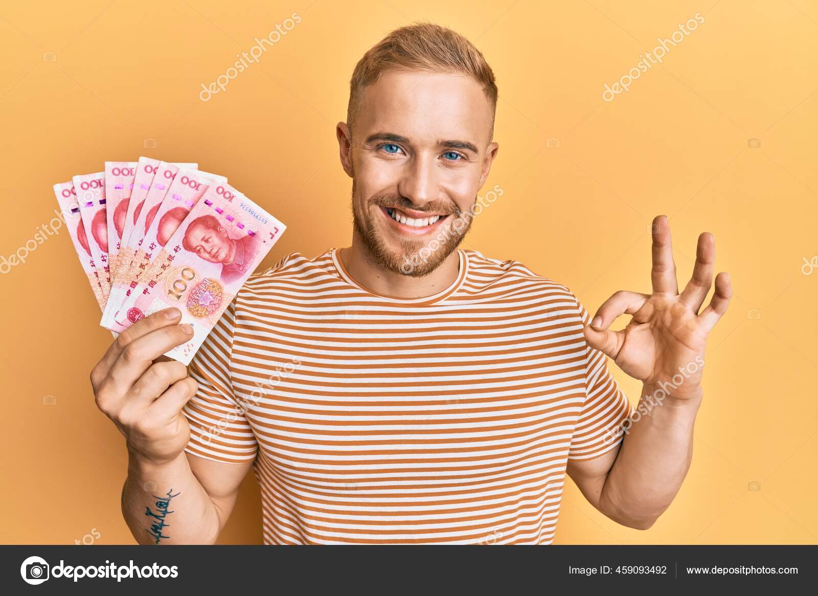 年轻的高加索人手里拿着100元人民币的中国钞票手拿着手签微笑着友好地摆姿势是个很好的象征——图库图片© Krakenimages.com  #459093492