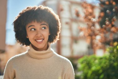 Genç İspanyol kız gülümseyerek şehirde mutlu mesut dikiliyor..