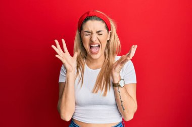 Beyaz gündelik tişört giyen genç beyaz kadın, başarı için deli ve çılgınlığı kutluyor. Kolları havada ve gözleri kapalı, heyecanlı bir şekilde bağırıyor. Kazanan konsept 