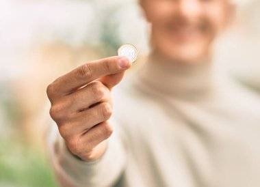 Genç İspanyol gülümseyen adam şehirde 1 Euro 'luk bozuk para tutuyor..