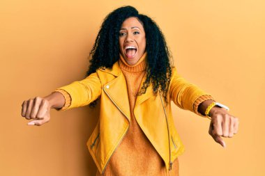 Orta yaşlı Afro-Amerikan kadın motosiklet sembolü yapıyor elleri çılgın kutlama yapıyor ve başarı için hayrete düşmüş gözleri açık heyecanla bağırıyor. 