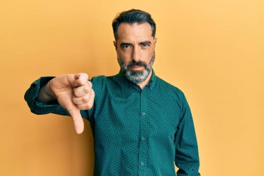 Orta yaşlı, sakallı, gri saçlı, iş kıyafetleri giyen, mutsuz, kızgın, reddedilmiş ve olumsuz davranışlı bir adam. kötü ifade. 