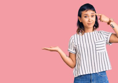 Rahat kıyafetler giyen genç bir kadın avuç içi boşluğu gösteren ve alnını işaret eden açık avuçlardan rahatsız oluyor. Bunu bir düşün.. 